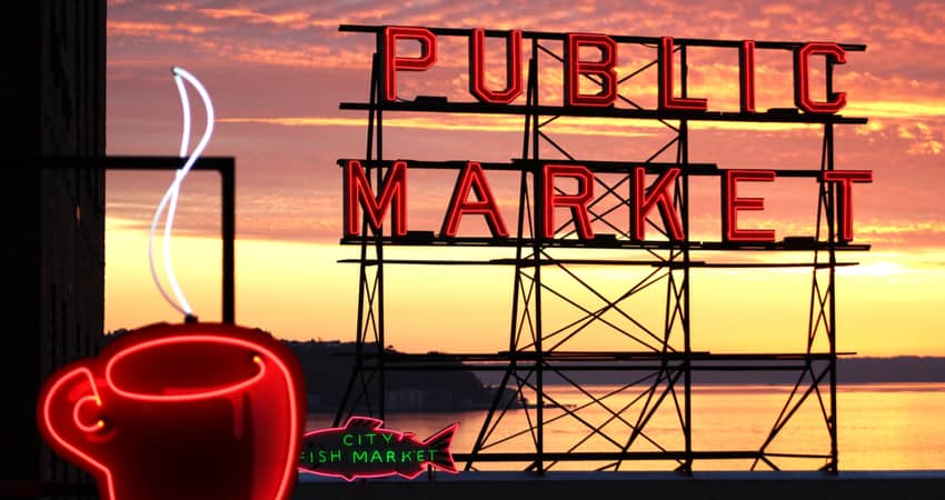 The neon Pike Place Market sign with the sunset in the background